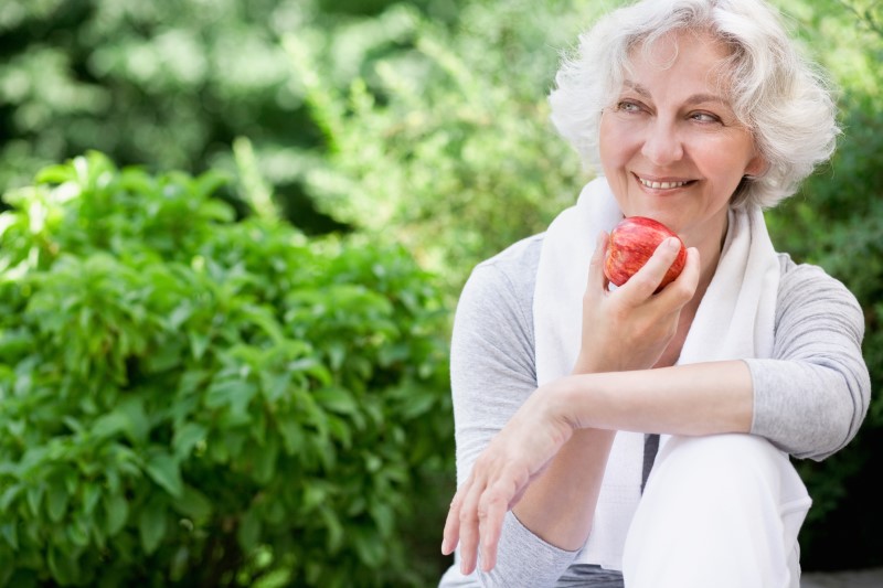 sportliche Seniorin mit Apfel draußen